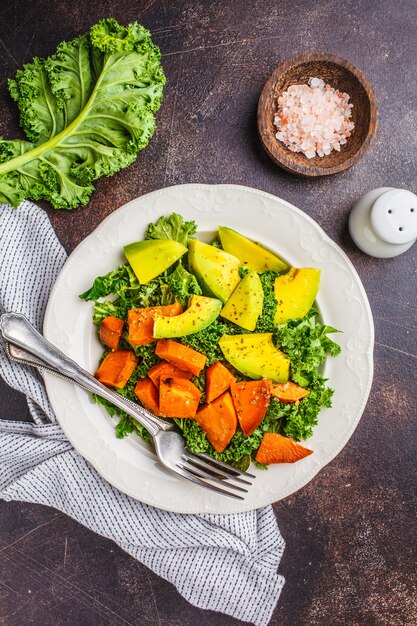 Salada verde saudável da couve com abacate e as batatas doces cozidas.