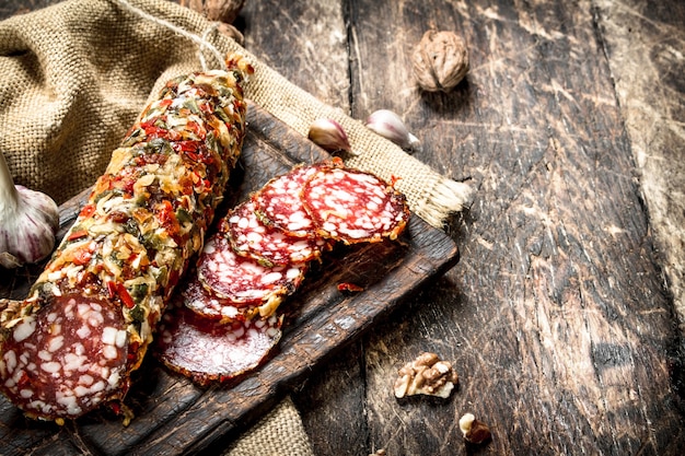 Salame com alho e nozes. Sobre um fundo de madeira.