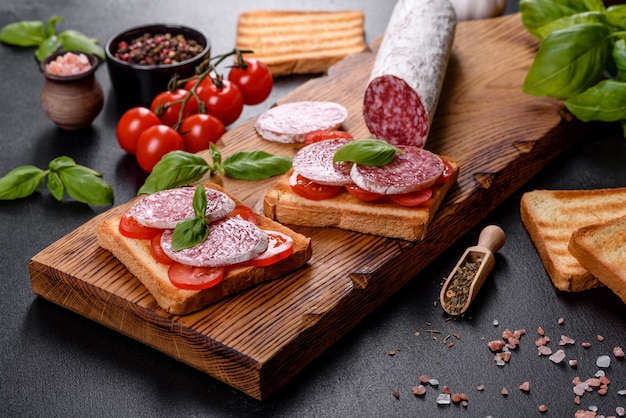 Salame de linguiça seca espanhola em um fundo escuro de concreto. Preparação de deliciosos sanduíches frescos