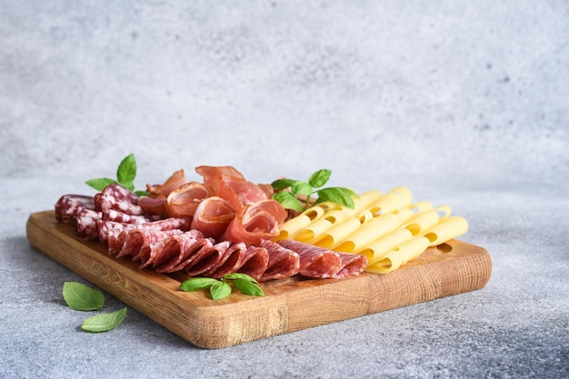 Salame de presunto de queijo em um tabuleiro quadrado de madeira Delicadeza