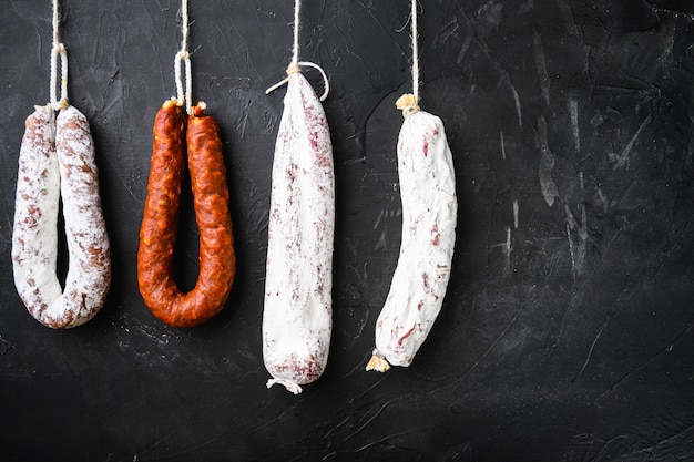 Salame espanhol, fuet e chouriço pendurados em uma prateleira