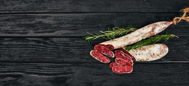 Salame Fuet e Alecrim Salsicha espanhola tradicional Em um fundo preto de madeira Vista superior