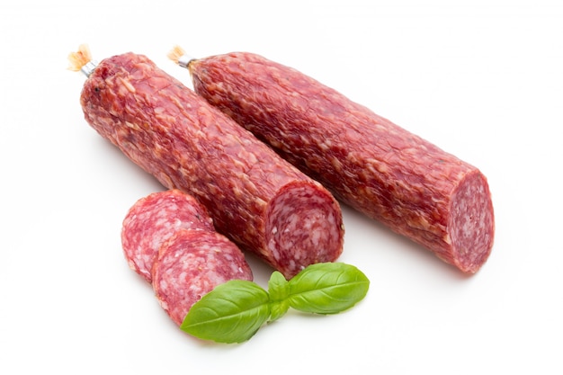 Salami geräucherte Wurst, Basilikumblätter und Pfefferkörner isoliert auf Weiß