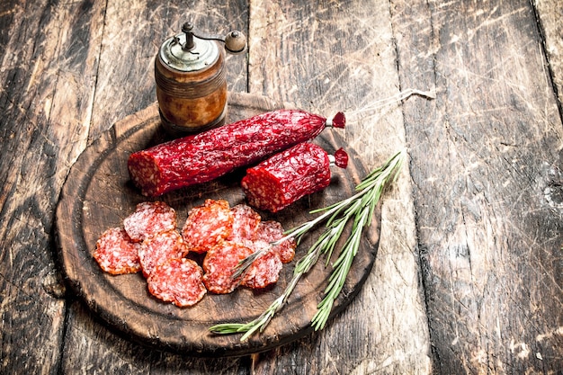 Salami con hierbas y especias en una placa sobre un fondo de madera