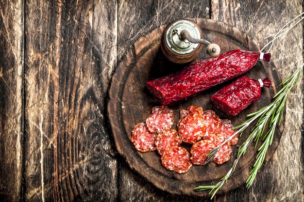 Salami con hierbas y especias en una placa sobre un fondo de madera