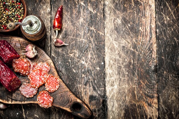 Salami con hierbas y especias en una placa sobre un fondo de madera