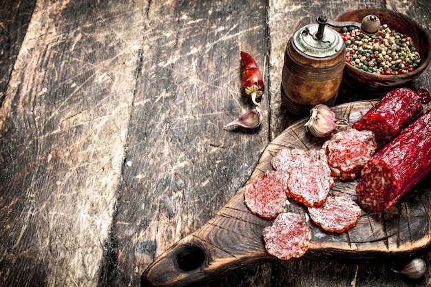 Salami con hierbas y especias en una placa sobre un fondo de madera