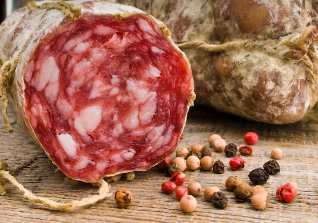 Salami italiano cerca de especias en mesa de madera