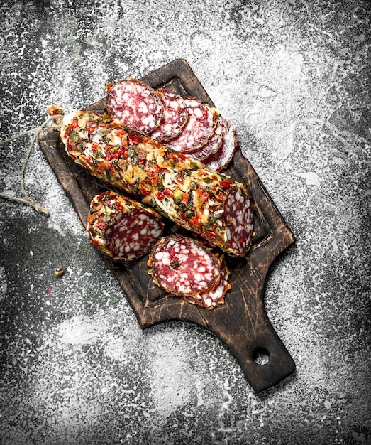 Salami mit Gewürzen und Kräutern. Auf einem rustikalen Hintergrund.