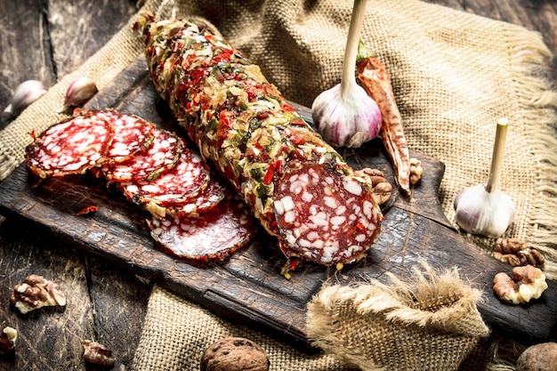 Salami mit Knoblauch und Nüssen. Auf einem hölzernen Hintergrund.