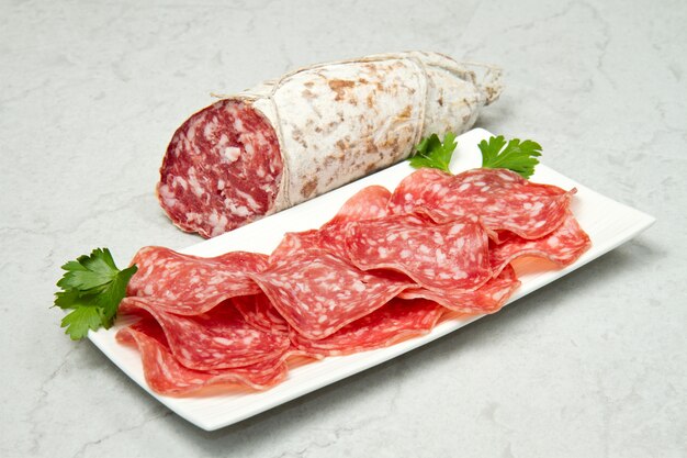 Salami rebanado en mesa de mármol