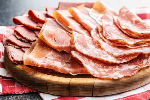 Salami en rodajas, prosciutto y rosbif sobre tabla de cortar