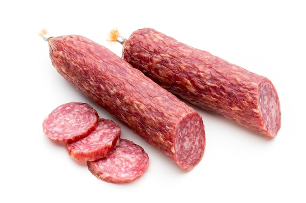 Salami salchicha ahumada, hojas de albahaca y granos de pimienta aislados sobre superficie blanca.