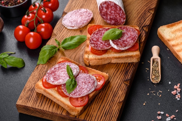 Salami de salchicha seca española sobre un fondo de hormigón oscuro. Preparación de deliciosos bocadillos frescos.