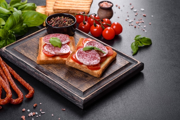 Salami de salchicha seca española sobre un fondo de hormigón oscuro. Preparación de deliciosos bocadillos frescos.