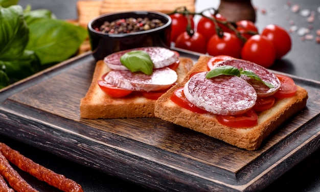 Salami de salchicha seca española sobre un fondo de hormigón oscuro. Preparación de deliciosos bocadillos frescos.