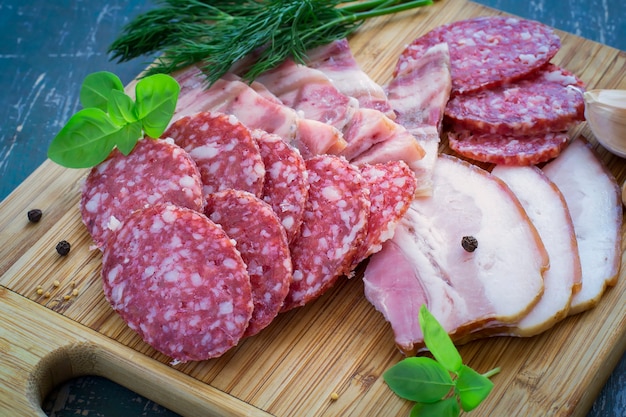 Salami, tocino y verduras en una tabla de cortar