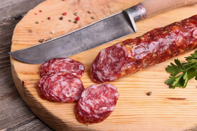 Salami und Messer auf einem Schneidebrett, Ansicht von oben