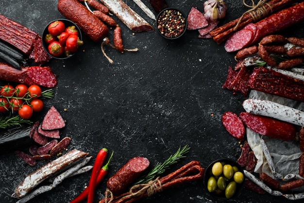 Salami und Snacks Wurst Fouet Würstchen Salami Paperoni auf schwarzem Steinhintergrund Draufsicht Freier Platz für Ihren Text