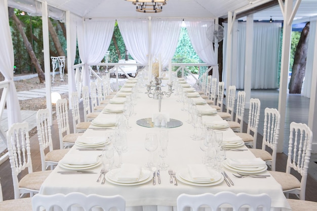 Salão de banquetes vazio pronto para receber convidados no terraço de verão. mesa festiva branca