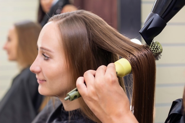 Salão de beleza feminino cabeleireiro secando o cabelo com um secador de cabelo