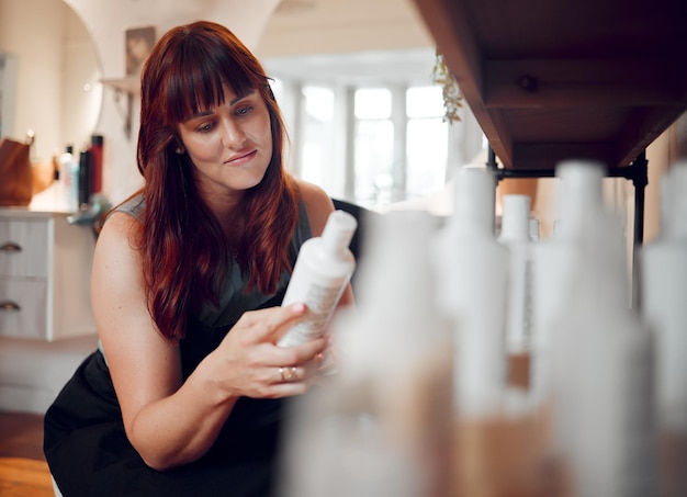 Salão de cabeleireiro e mulher estilista profissional lendo shampoo ou produtos de tratamento de beleza de queratina para cuidados com os cabelos Mulher feliz ou proprietária em negócios de cabeleireiro de inicialização enquanto verifica o inventário