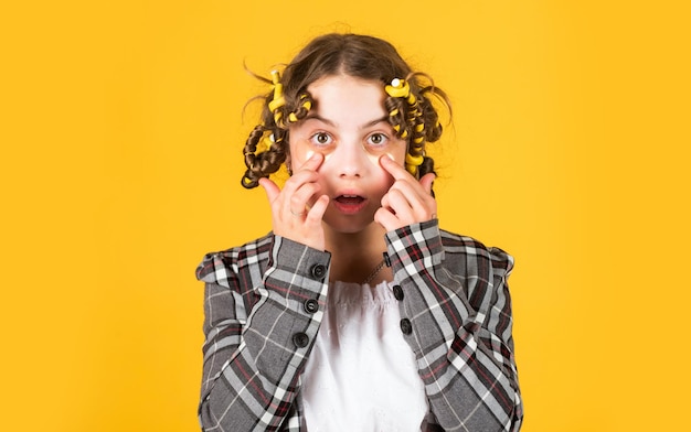 Salão de cabeleireiro Menina com rolinhos e grampos de cabelo no cabelo em fundo amarelo Encrespadores de menina ao redor do cabelo Criar penteado bonito Penteado lindo Criança feliz com tapa-olhos