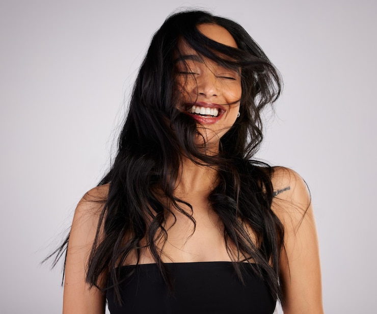 Foto salão de cuidados com o cabelo e mulher com vento no estúdio para o crescimento tratamento de queratina ou shampoo em fundo branco penteado estético e modelo feliz com os olhos fechados para satisfação brilho ou glamour