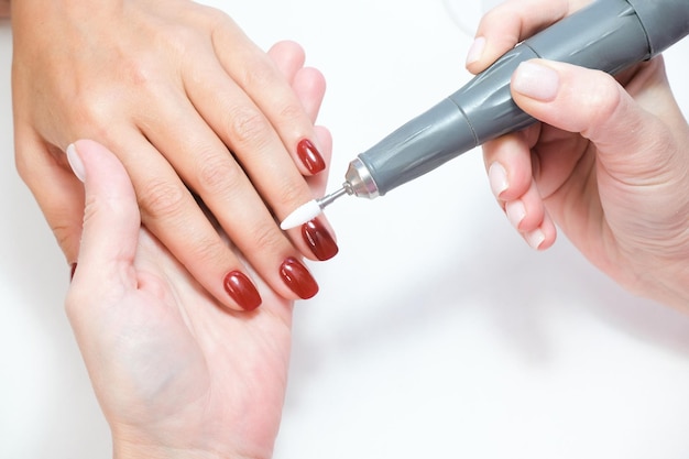 Salão de esteticista, manicure. manicure profissional de hardware usando máquina elétrica no salão de beleza. mestre usa uma máquina elétrica para remover esmalte das mãos durante a manicure