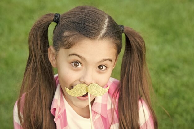 Foto salão de fotos criança feliz com bigode falso festa de menina brincalhona na grama verde salão de beleza olho elegante salão de design de cabelo salão de cuidados que você merece