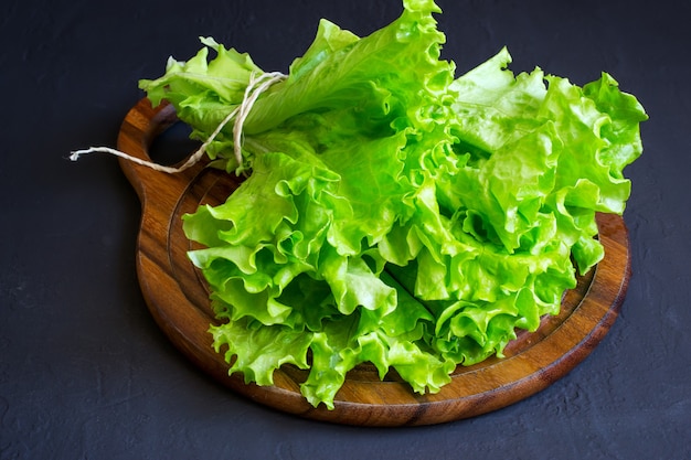 Salat auf einem Holzbrett auf dunklem Hintergrund.