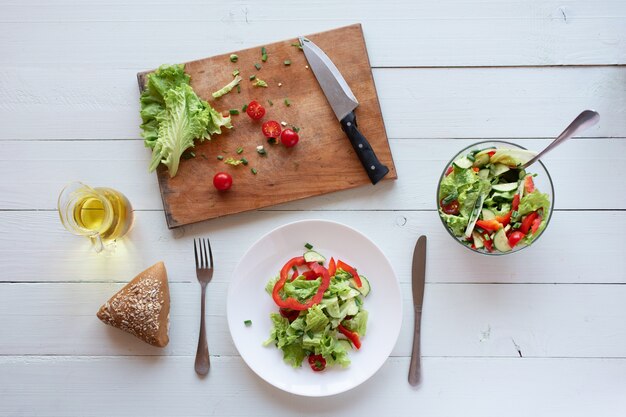 Salat auf einem weißen hölzernen Hintergrund von Tomaten, Gurke, Salat und rotem Pfeffer. Konzept für gesunde Ernährung.