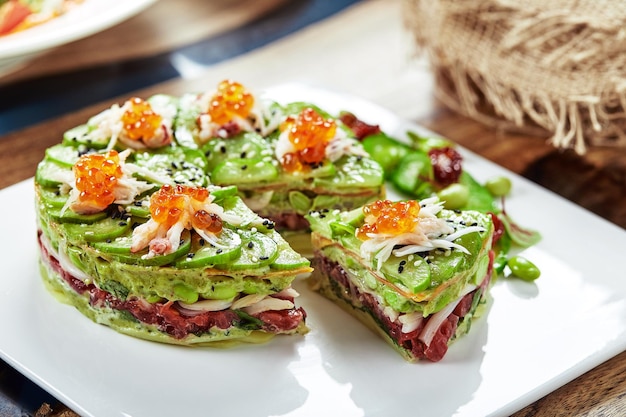 Salat aus Avocado, Meeresfrüchten, Fleisch, Gemüse und Kürbiskernen. Diätetisch, gesund und lecker. Festliche Bankettgerichte. Speisekarte des Gourmetrestaurants. Weißer Hintergrund.