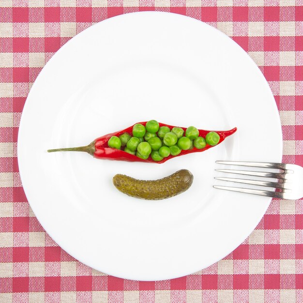 Foto salat aus eingelegten und eingelegten erbsen, gurken und rotem pfeffer auf einem weißen teller.