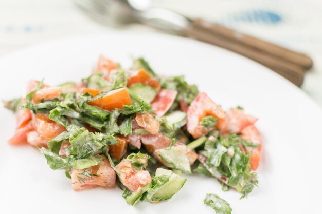 Salat aus frischem Gemüse, Gurke, Tomatengrün mit Sauerrahm