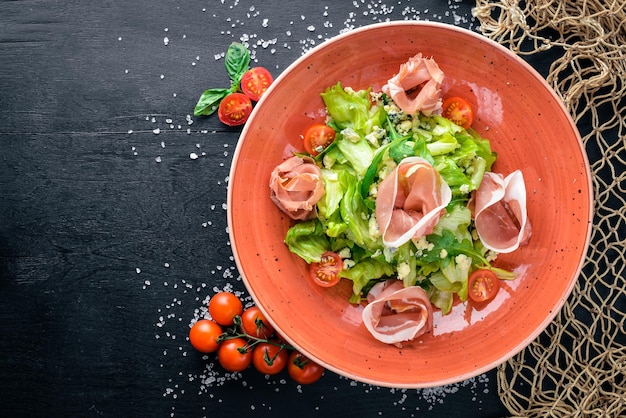 Salat aus frischem Gemüse und Speck. Caesar. Auf einem hölzernen Hintergrund. Ansicht von oben. Freiraum für Ihren Text.