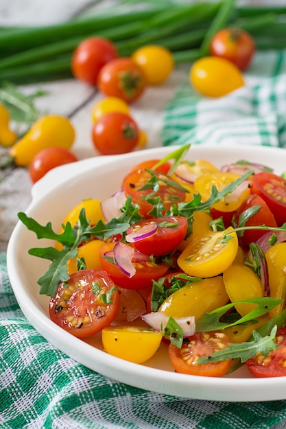 Salat aus frischen Kirschtomaten mit Zwiebeln und Rucola