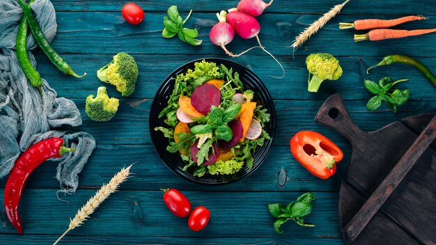 Salat aus frischen Rüben, Tomaten und Kopfsalat Gesundes Essen auf einem blauen Holztisch Draufsicht Freier Platz für Text