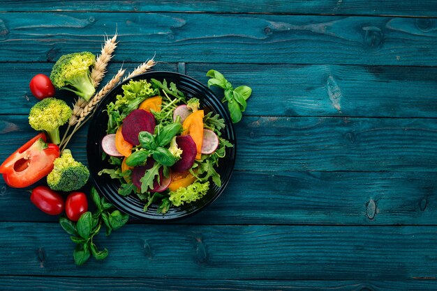 Salat aus frischen Rüben, Tomaten und Kopfsalat Gesundes Essen auf einem blauen Holztisch Draufsicht Freier Platz für Text