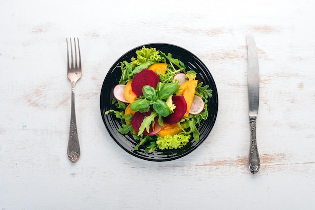 Salat aus frischen Rüben, Tomaten und Kopfsalat Gesundes Essen auf einem weißen Holztisch Draufsicht Freier Platz für Text