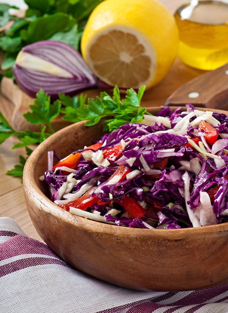 Salat aus Rot- und Weißkohl und süßem rotem Pfeffer, gewürzt mit Zitronensaft und Olivenöl in Holzschale