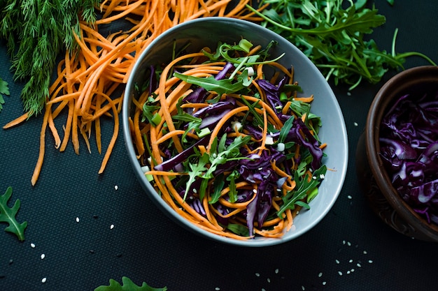 Salat aus Rotkohl, Karotten und Gemüse. Mit geschnittenem Gemüse und Kräutern dekoriert.