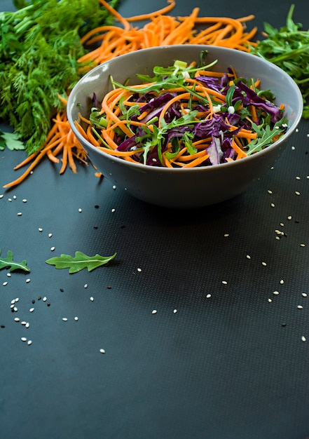 Salat aus Rotkohl, Karotten und Gemüse. Mit geschnittenem Gemüse und Kräutern dekoriert.