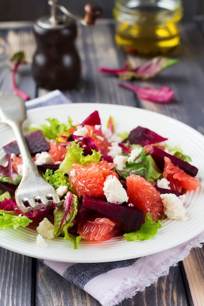 Salat aus Rüben, Salat, Rote-Bete-Blättern, Grapefruit und Feta-Käse auf dem alten Holztisch.