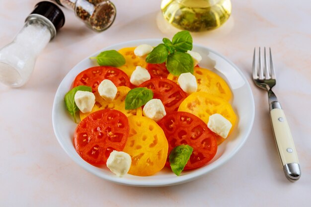 Salat aus Tomaten, Mozzarella, Basilikum und Olivenöl mit Gabel.