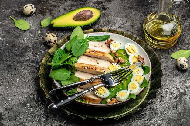 Salat Avocado gegrilltes Hähnchenfilet Wachtelei Spinat Walnuss auf dunklem Hintergrund Keto-Diät Gesunde Fette Sauberes Essen zur Gewichtsabnahme Langes Bannerformat Draufsicht