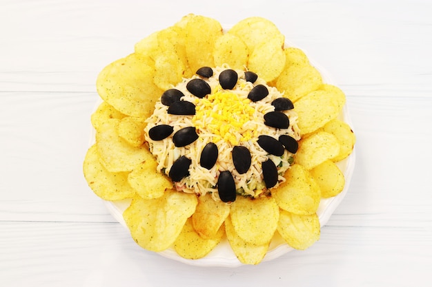 Salat in Form von Sonnenblumen, dekoriert mit Kartoffelchips auf einem Teller