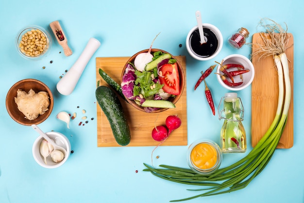 Foto salat machen. tischbesteck und dressing-bestandteile für frischen salat auf hellblauem hintergrund, draufsicht