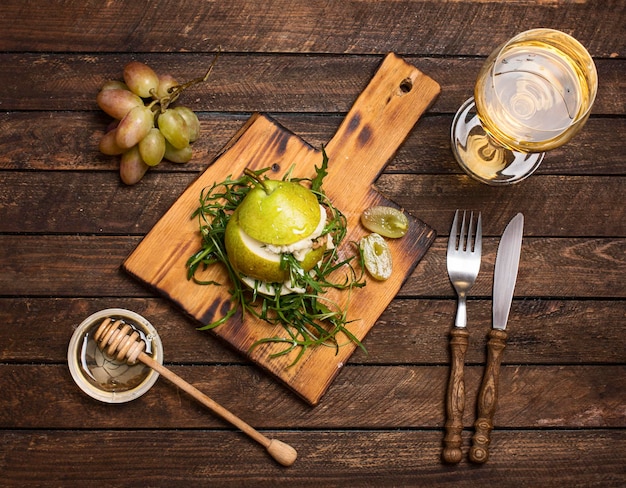 Salat mit Arugula-Stracciatella-Nuss-Trauben und Honig in Birnen überbacken auf Holzschneidebrett