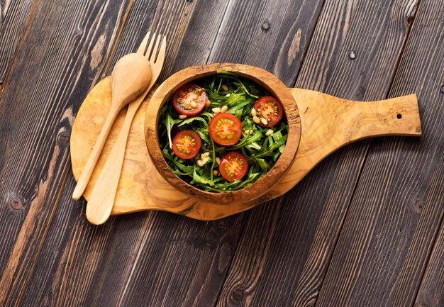 Salat mit Arugula-Tomaten und Pinienkernen in einer Holzschüssel-Draufsicht